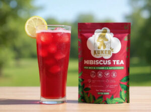 Hibiscus tea in a glass with lemon slice next to a tea bag package.