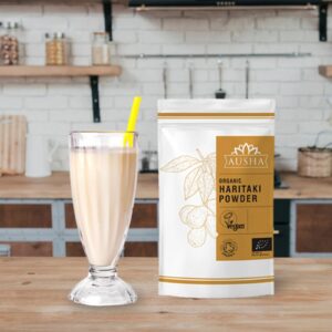 Organic Haritaki Powder package next to a glass of smoothie