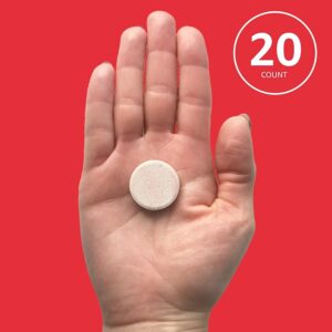 Effervescent milk thistle tablet in a hand against a red background.